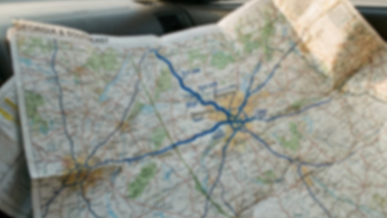 Unfolded paper road map spread across a car seat — analog navigation before GPS — The Rad Rewind