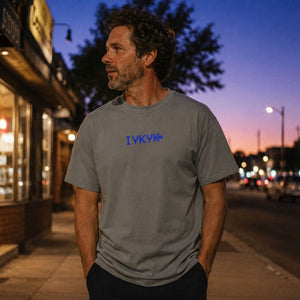 The Rad Rewind IYKYK Graphic Tee in Granite — lifestyle front shot at twilight on urban sidewalk