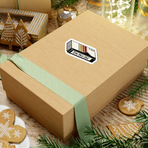 3 by 3 inch I'm This Old retro VHS cassette sticker applied to a kraft gift box among holiday decorations
