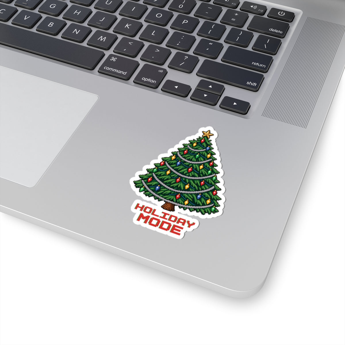 3 by 3 inch Holiday Mode pixel Christmas tree sticker applied to a laptop beside the keyboard