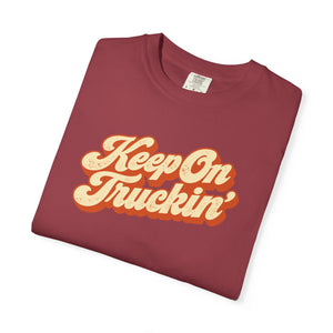 Chili brick red garment-dyed graphic tee with Keep On Truckin' in leaning cream script and a burnt-orange shadow, folded