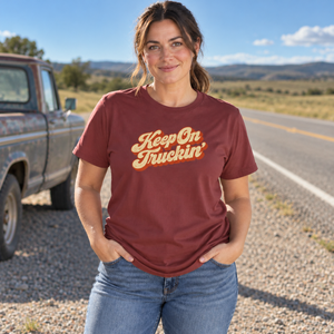 Woman with a brunette ponytail wearing the Chili Keep On Truckin' graphic tee beside an old pickup on an open highway shoulder