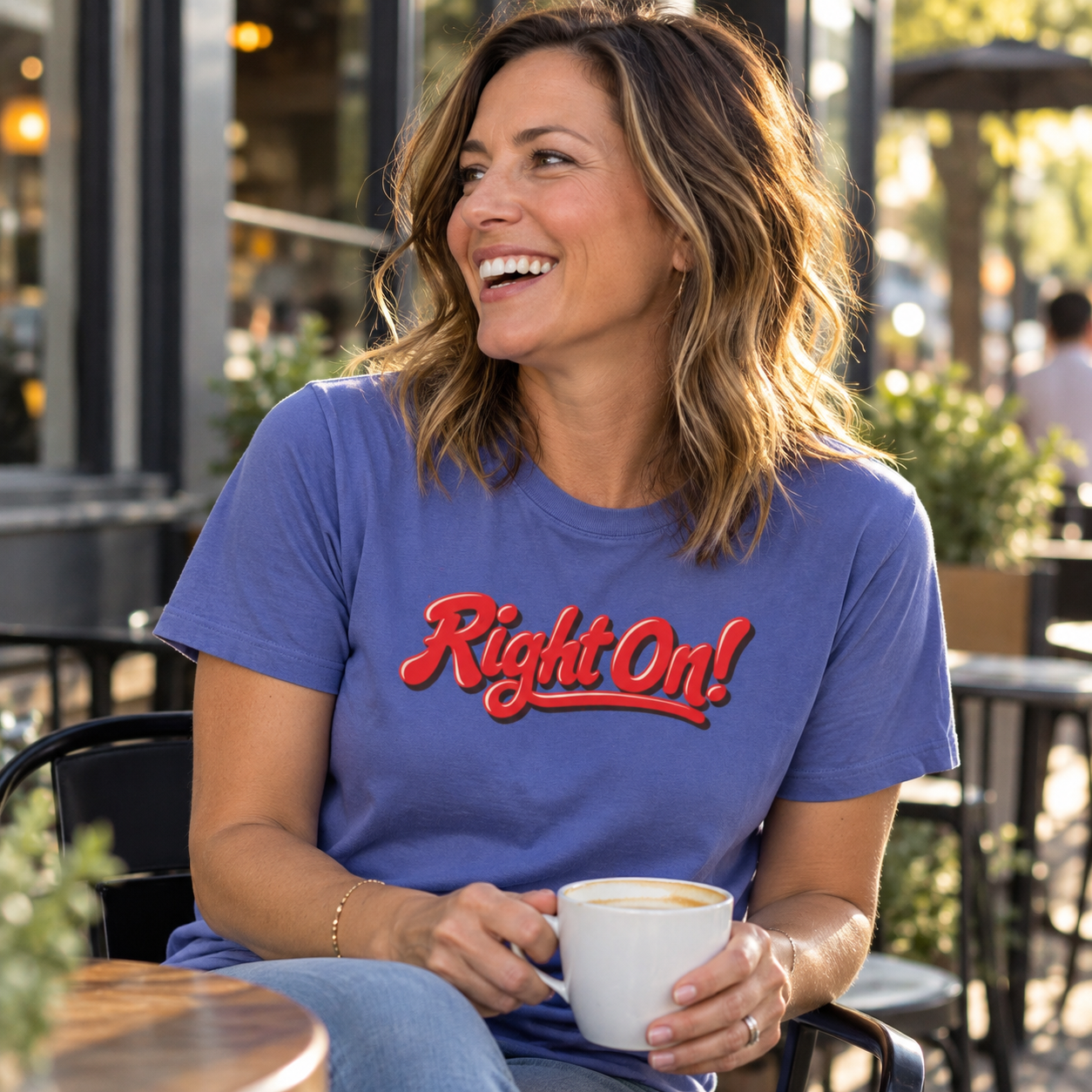 Laughing woman with a latte wearing the Periwinkle Right On! graphic tee on a café patio