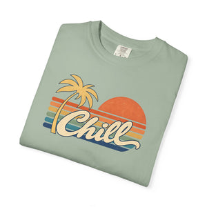 Bay sage green garment-dyed graphic tee with a retro sunset, leaning palm tree, faded stripes and cream Chill script, folded