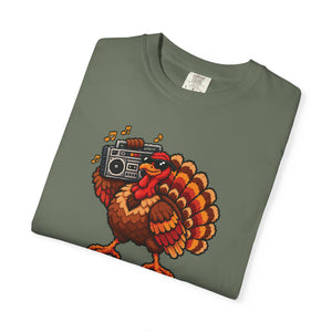 Moss sage green garment-dyed graphic tee with a pixel-art turkey in sunglasses carrying a boombox, folded