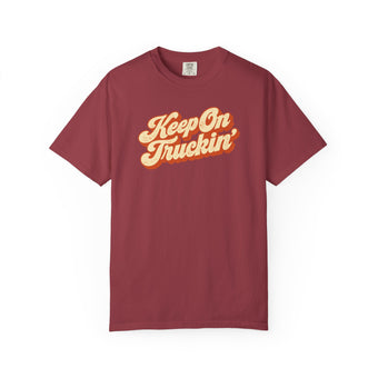 Chili brick red garment-dyed graphic tee with Keep On Truckin' in leaning cream script and a burnt-orange shadow, front view