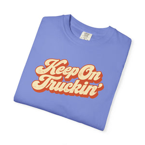 Flo Blue periwinkle garment-dyed graphic tee with Keep On Truckin' in leaning cream script and a burnt-orange shadow, folded