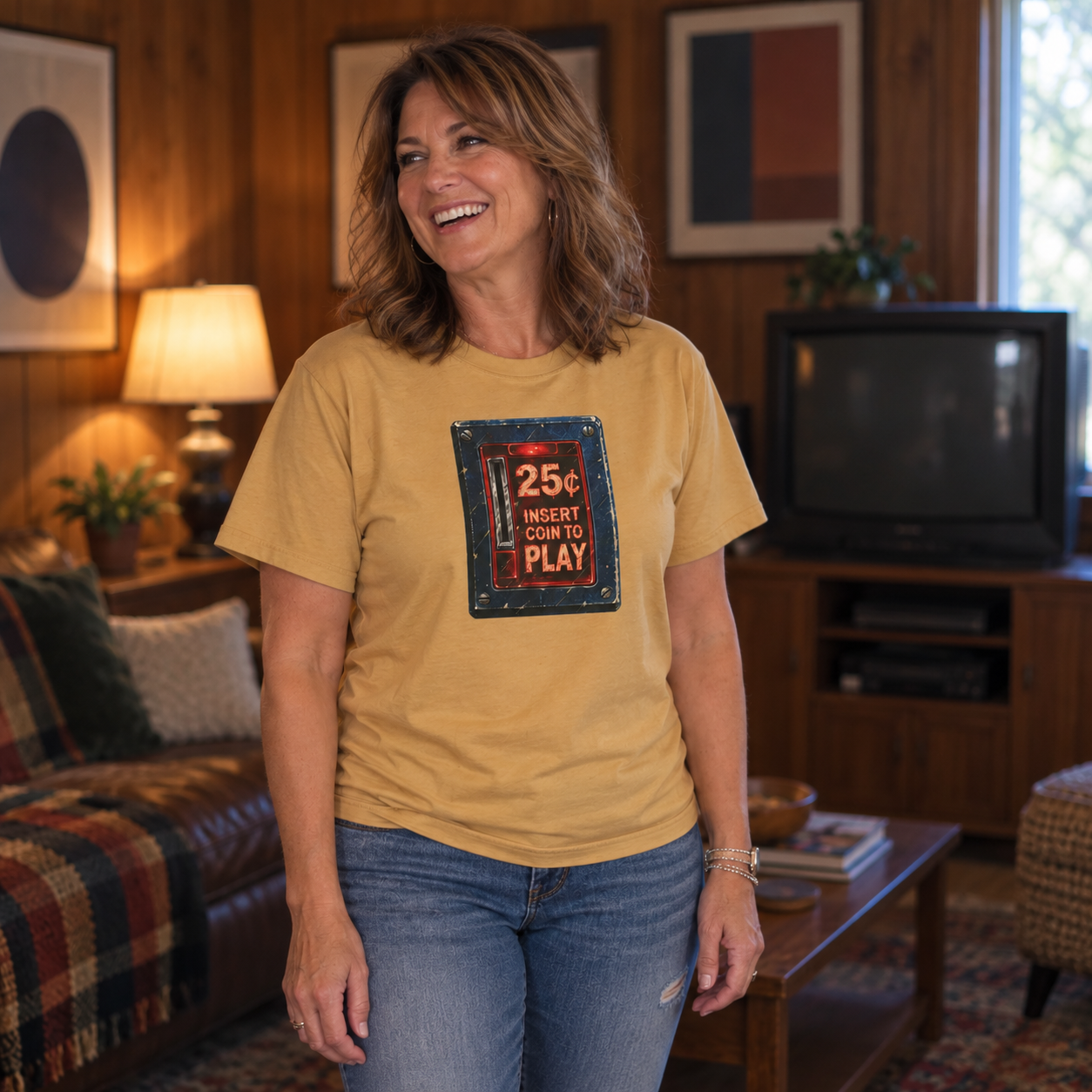 Woman wearing a mustard yellow retro arcade coin door graphic tee in a wood-paneled rec room